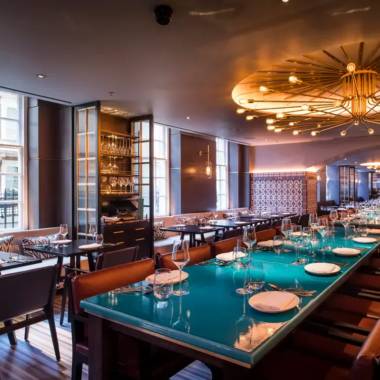 The interior of the restaurant with tables and chairs and tall windows at Rüya London.