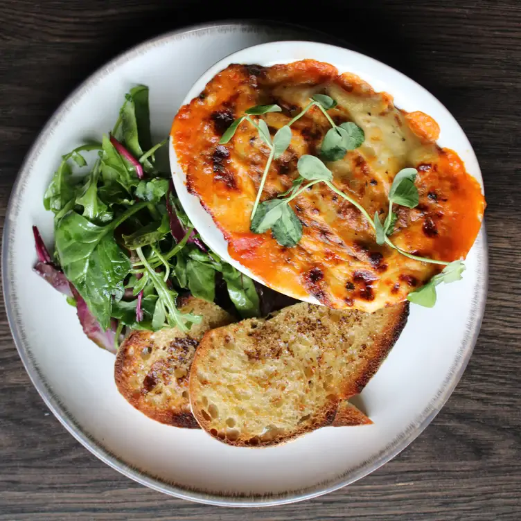 A lasagne dish with bread and salad at Mharsanta, one of the best romantic restaurants in Glasgow.