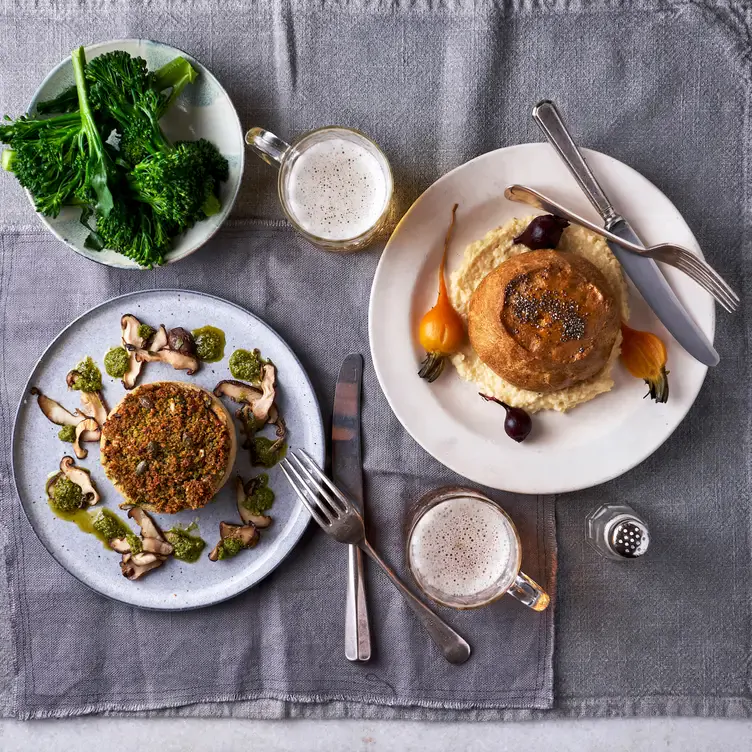 Plates of food with green vegetables at The Anthologist One St Peter’s Square, one of the best brunches in Manchester.