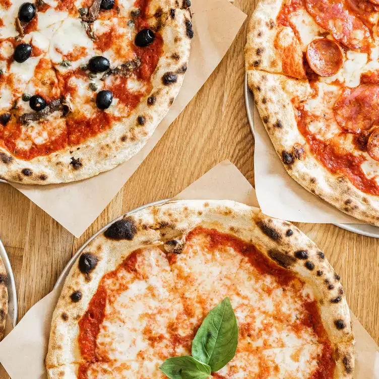 Three pizzas on a table at The Pizza Room, one of the best family-friendly restaurants in London.