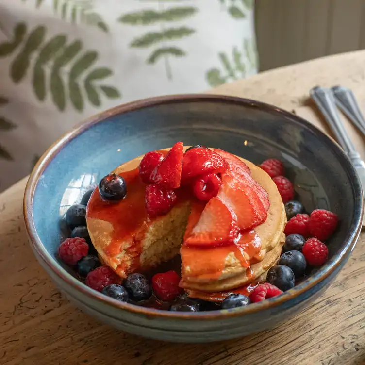 Fluffy pancakes layered with syrup and fresh berries at one of the best brunch spots in London.