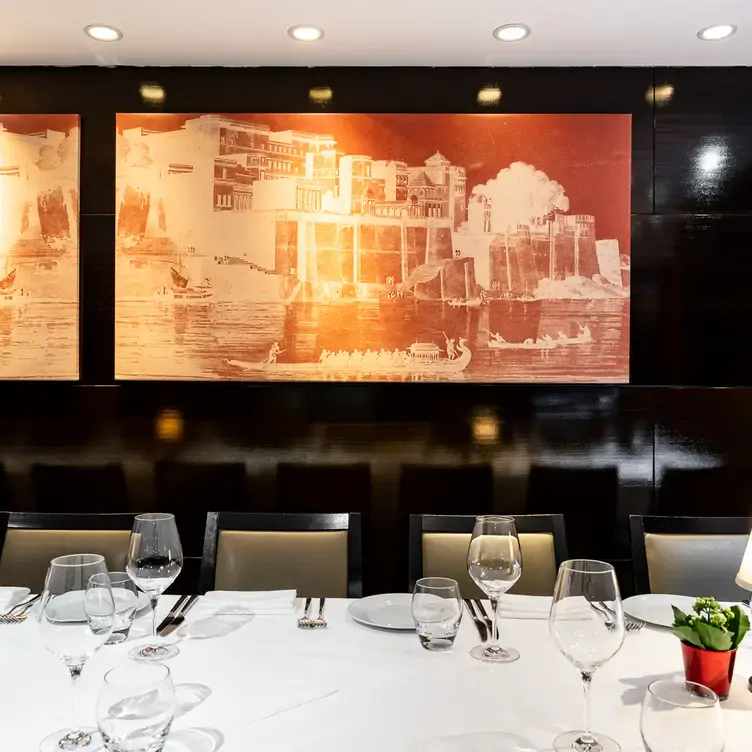 A table at Benares with white and orange illustrations on the wall behind it.