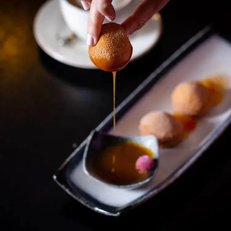 A croquette being dipped in sauce at Leicester Square Kitchen.