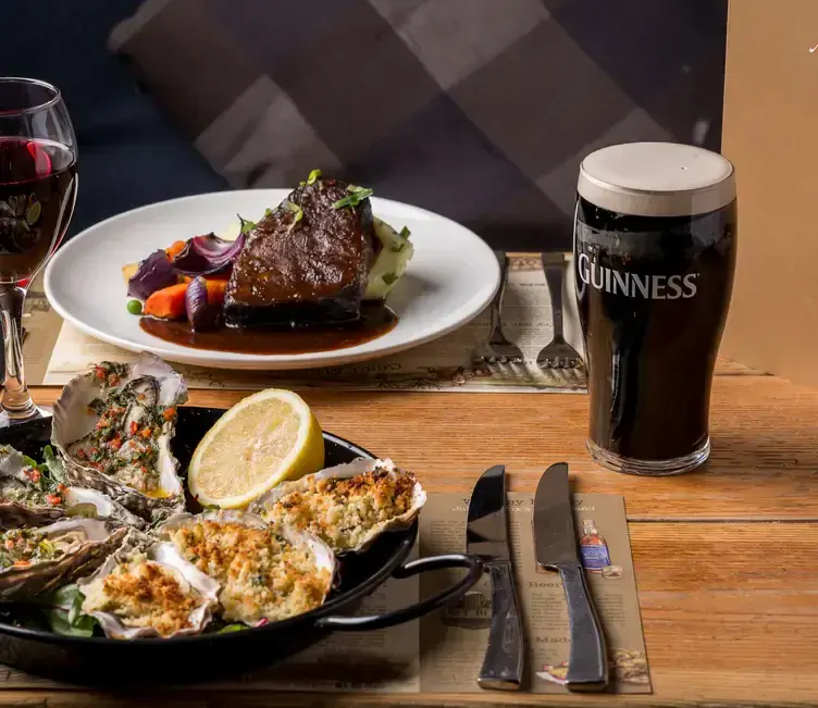 A plate of oysters and a plate of steak served alongside a Guinness and red wine at Johnnie Fox’s, one of the best pubs in Dublin.