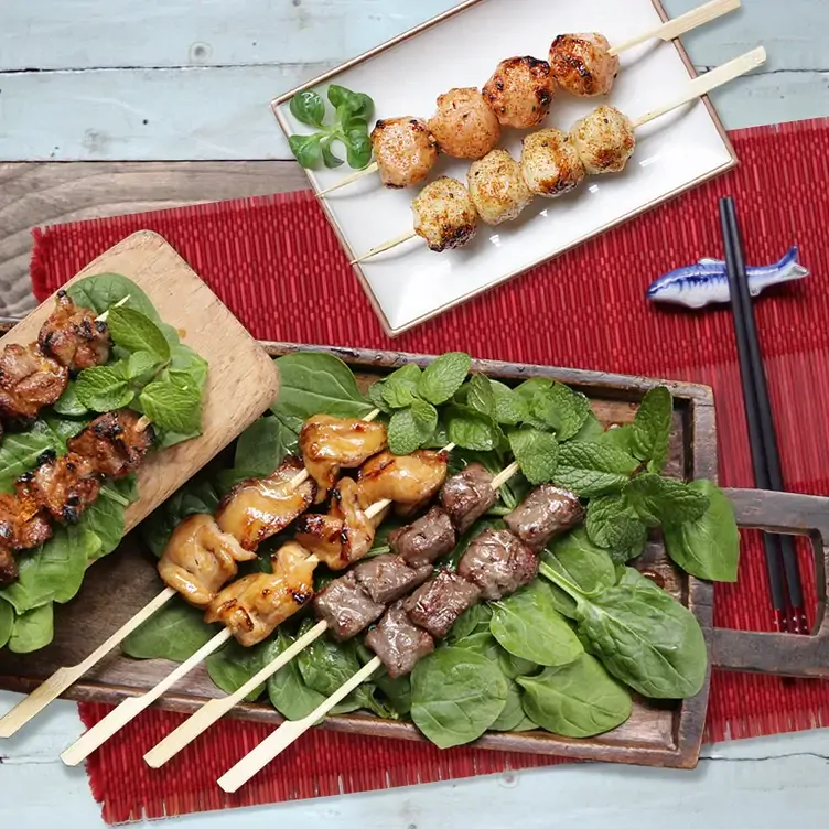 Grilled meat skewers on greens at Baozilnn, one of the best dim sum restaurants in London