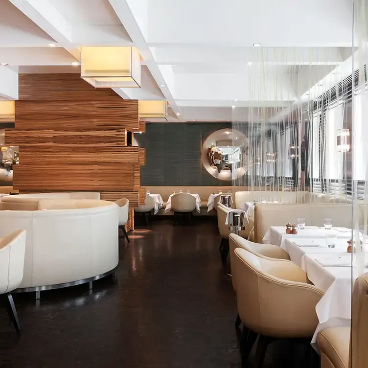 The interior of Locanda Locatelli, with tables surrounded by cushioned armchairs and booths.