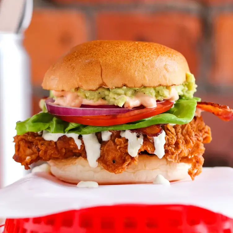 A chicken burger with bacon, avocado, lettuce, and tomato at Almost Famous, one of the best bottomless brunch restaurants in Manchester.