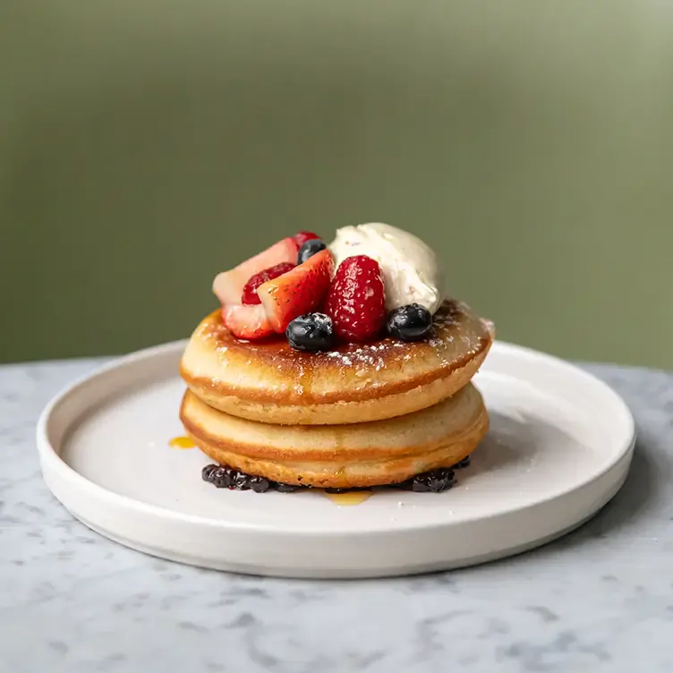 A plate of fluffy pancakes with strawberries and ice cream at Champagne Central, one of the restaurants with the best brunches in Glasgow.