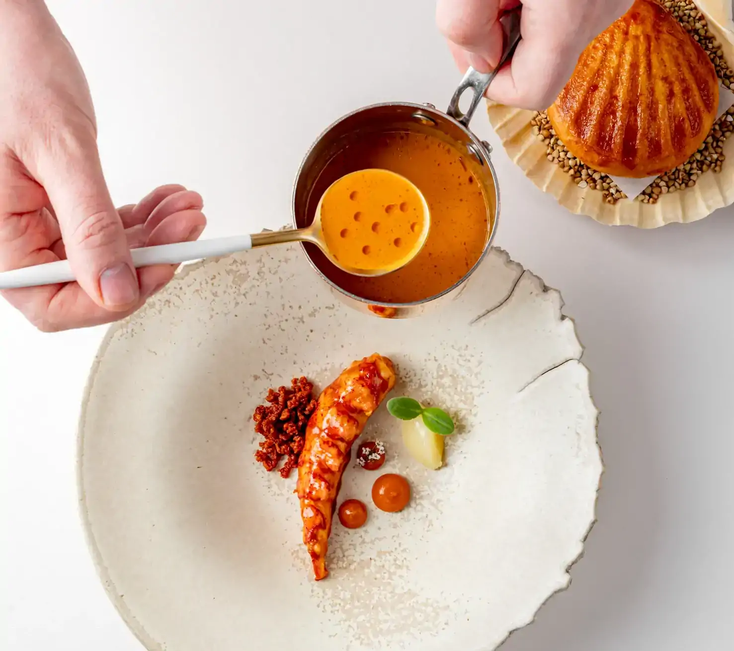 A waiter pours sauce over a seafood dish at Frog by Adam Handling, a MICHELIN restaurant in London