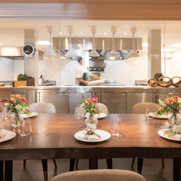 A dining table with flower bouquets and a open restaurant kitchen in the background at CORE by Clare Smyth, one of the best 3 MICHELIN stars restaurants in London.