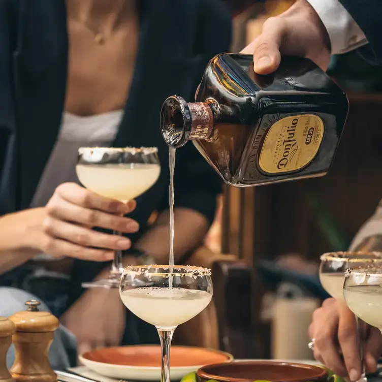 A waiter pours tequila into a cocktail glass at 100 Wardour Street Drinks, one of the best live music restaurants in London.