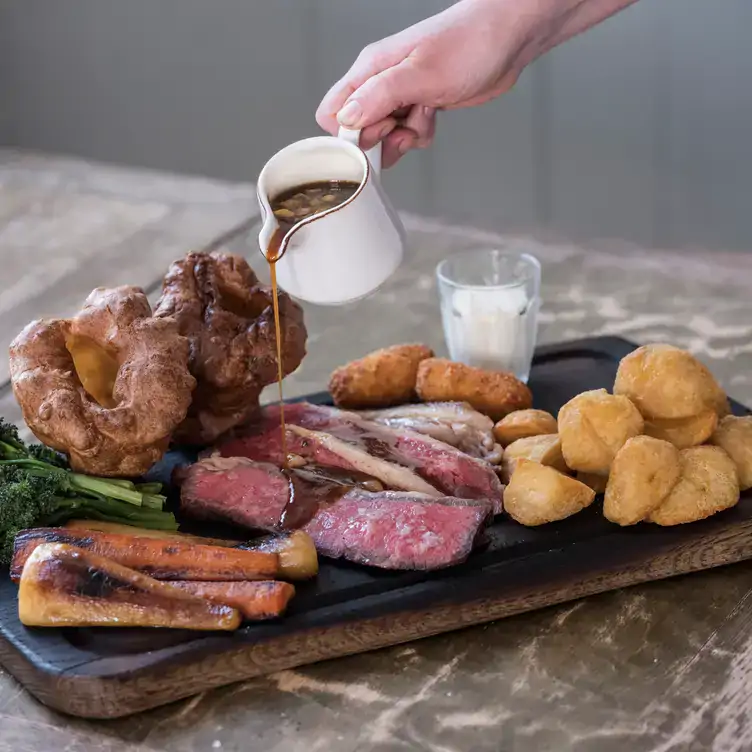 A savoury pastry dish served at Harwood Arms, A waiter pours gravy over a sharing board of Sunday roast at Harwood Arms pub, one of the best MICHELIN restaurants in London.