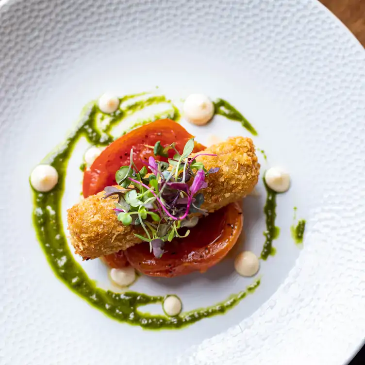 A croquette dish on a tomato with garnish at Bon Appetit.