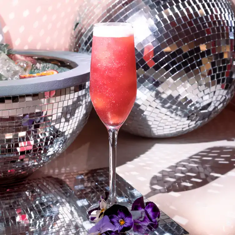 A pink gin mojito cocktail in front of a disco ball bowl with ice at Doll Society.