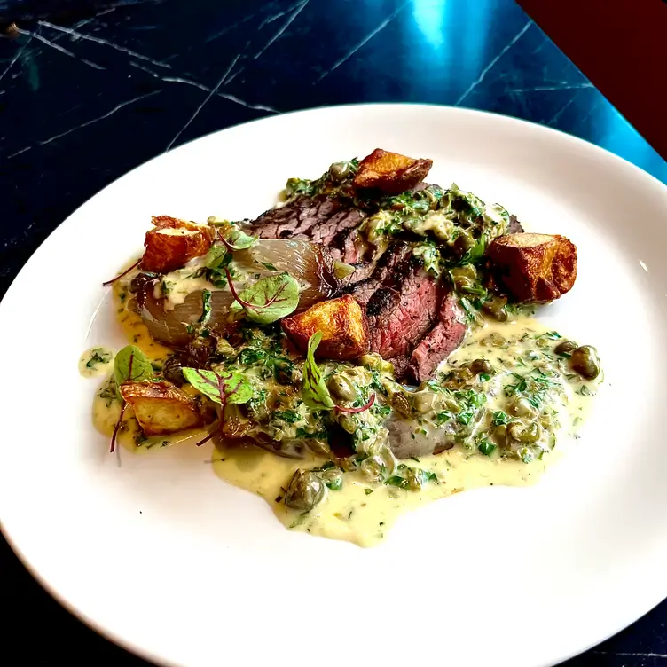 A sliced steak with herb sauce and potatoes at Lottie’s, one of the best restaurants in Dublin Ireland.