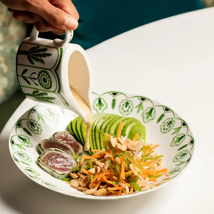 A diner pours a dressing over a tuna and avocado salad at Charlie’s, one of the best live music restaurants in London.