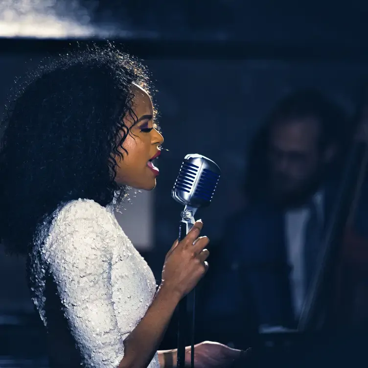 A singer sings into the microphone at The Parlour at The Ned London, one of the best music restaurants in London.