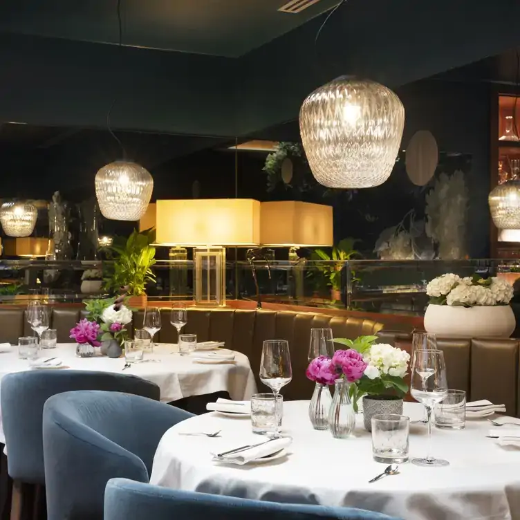 An elegant fining room with white tablecloths and hanging chandeliers at Pied à Terre in London