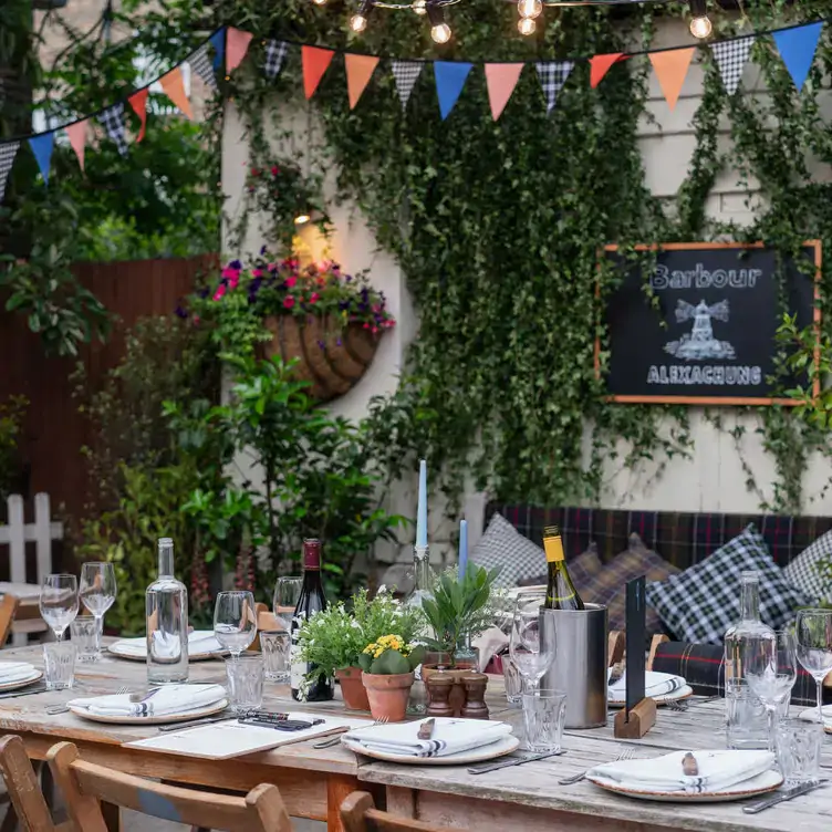 A table laid with wine bottles and candles in The Albion beer garden, one of the best beer gardens in north London.