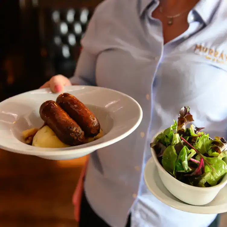 A waiter carries a dish of sausages and a small salad at Murray’s Bar, one of the best large beer gardens in Dublin.