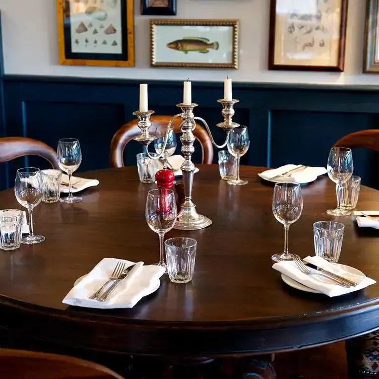 A large round table with place settings in the dining room of City Barge, one of the best riverside restaurants in London.