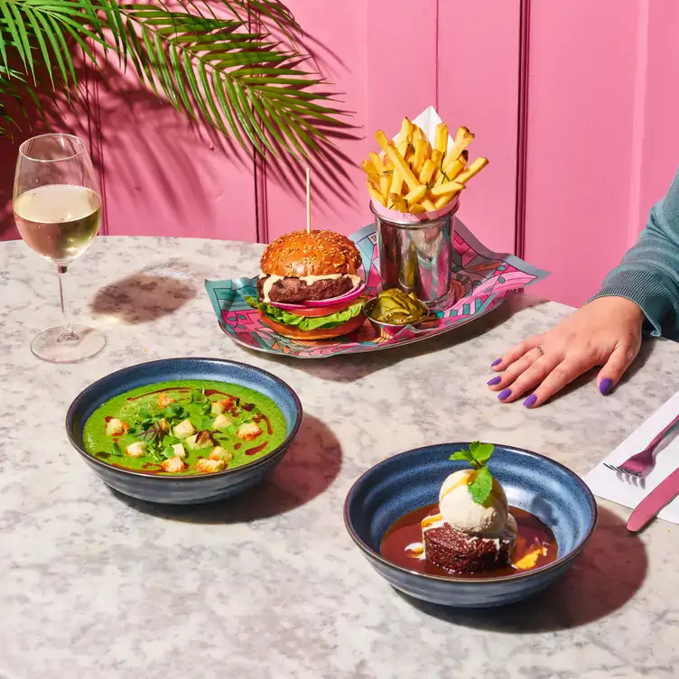 A lively table set with a gourmet burger, crispy fries, vibrant soup, and a decadent dessert, the perfect spread for a bottomless brunch in Birmingham.