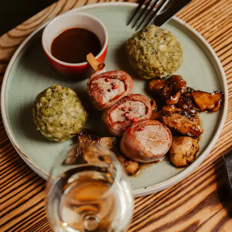 A white plate featuring a meatball skewer with two crumbed balls at Restaurant Jäger & Lustig, one of the best restaurants in Berlin.