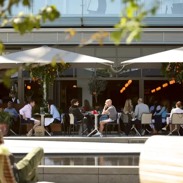 Diners sit at tables on the outside terrace at Fiume, one of the best riverside restaurants in London.