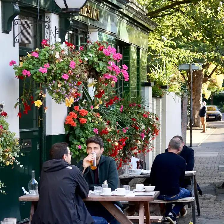 People drinking beer outside The Swan Pub, one of the best pubs with a garden in London.