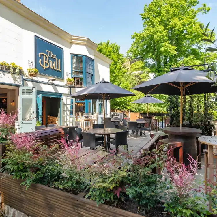 Tables with umbrellas on the patio at The Bull, one of north London’s best beer gardens.