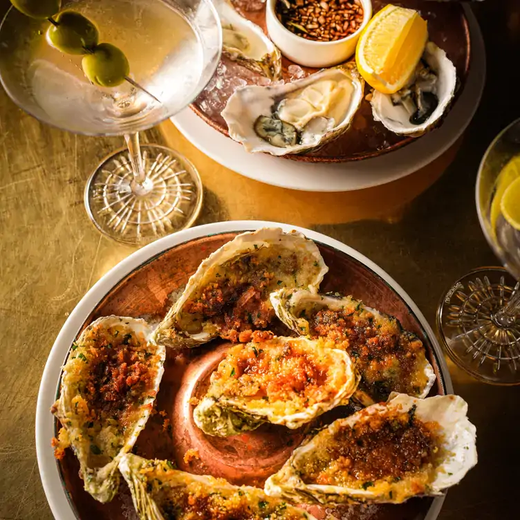 A dish of bone marrow oysters and traditional oysters with a cocktail at The Lowback Bar, one of the best riverside restaurants in London.