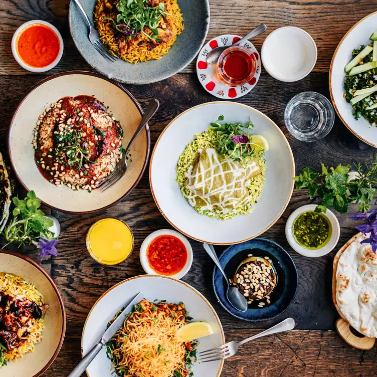 A table of dishes with hummus, rice, tandoor bread with spices and sauces at Villa Mama’s, one of the best restaurants in Chelsea, London.