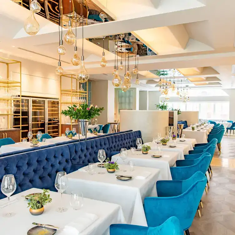 The bright interiors of A fine dining dish at CORD by Le Cordon Bleu in London, with white tablecloths and blue banquettes