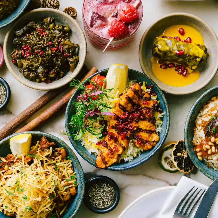 A table of various dishes with a cocktail and raspberry garnish, at Villa Mama’s in Chelsea.