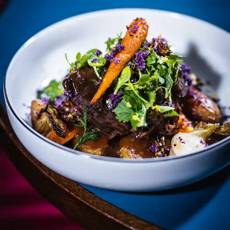 A dish topped with herbs and baby carrots at Pamela Popo, one of the best restaurants in Paris.