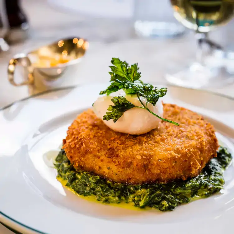 A dish of smoked haddock and salmon fishcake with poached egg at The Ivy Chelsea Garden, one of the best restaurants in Chelsea, London.