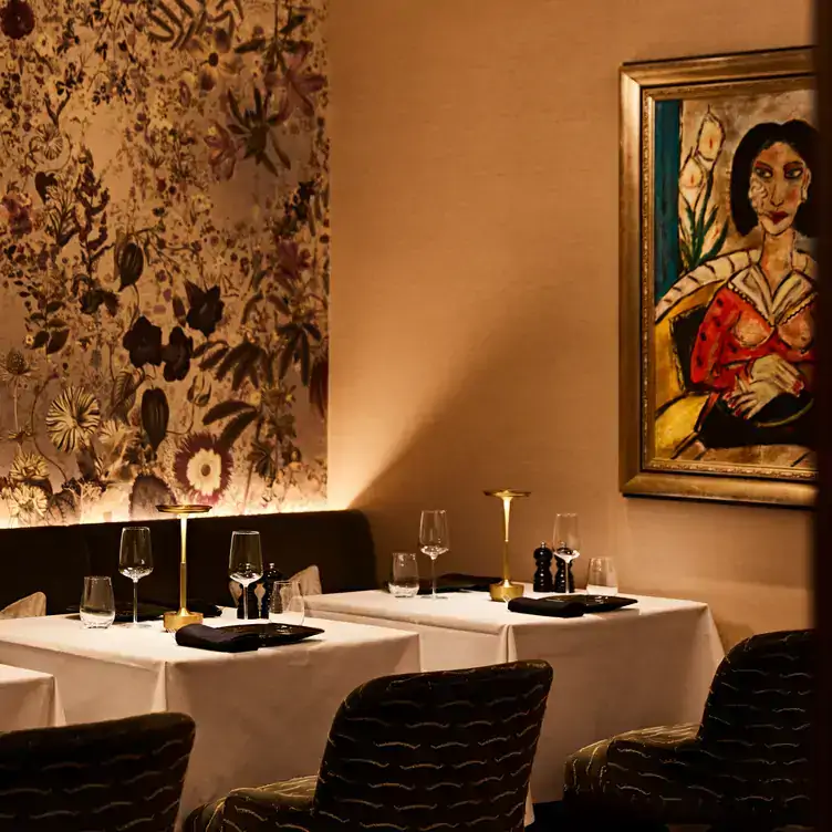 The interiors at Francatelli, with floral wallpaper, a painting and white tablecloths