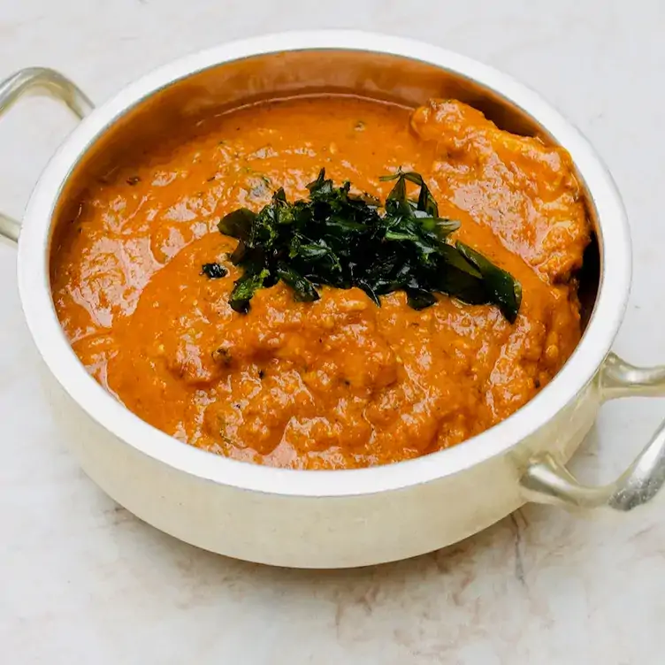 A masala curry in a serving dish with a spinach garnish on top at Kutir, in Chelsea.