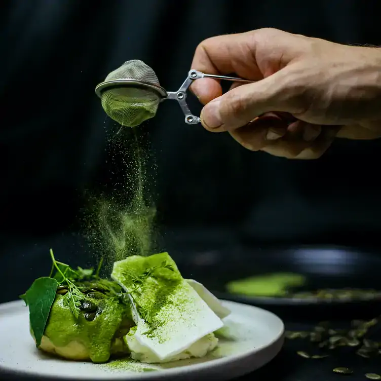 Someone dusts green powder over a dish at Mâche, one of Paris’ best restaurants.