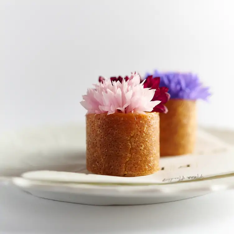 Two small cakes topped with pink and purple flowers served at Frog by Adam Handling.