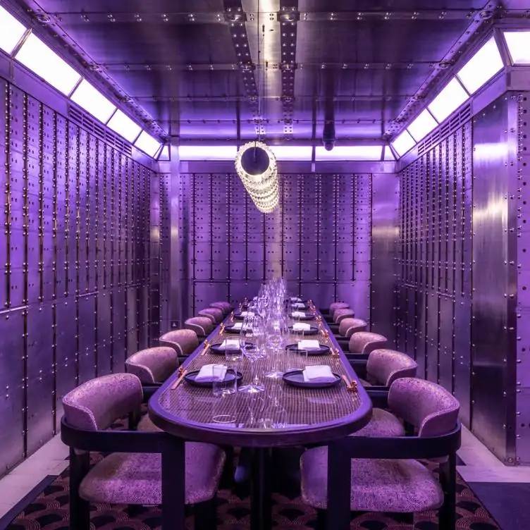 A long table in a private dining room at Lucky Cat in Manchester, with purple lighting and metallic walls.