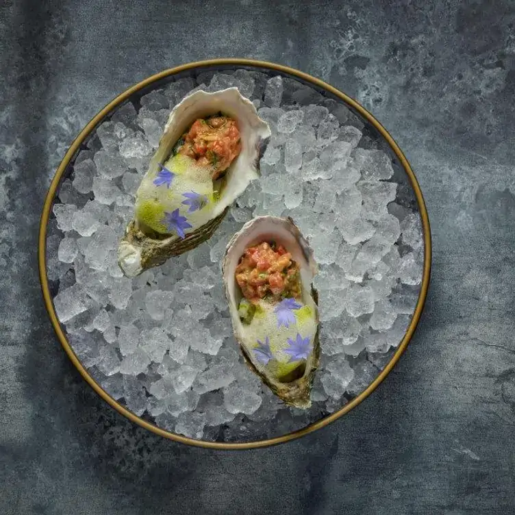 Two oysters sit on a bed of ice in a plate at Kanpai Classic Soho