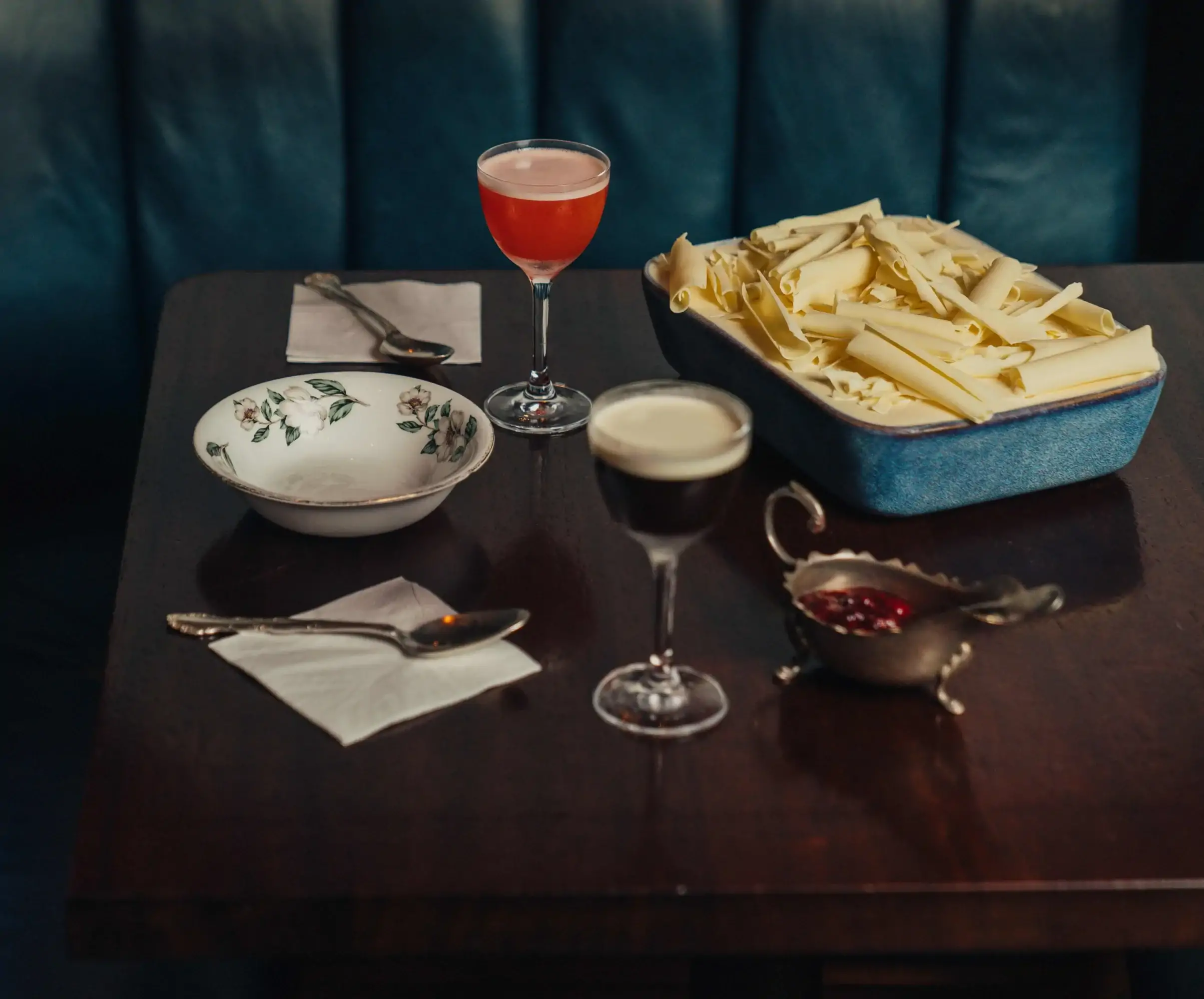 A white chocolate cheesecake tray sits on a table next to two cocktails at Blacklock in London