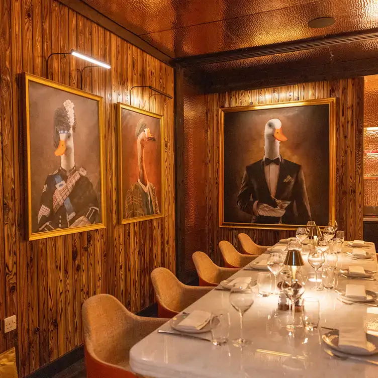 A private dining room at Duck & Waffle Edinburgh, featuring unique duck portraits on wooden-panelled walls, considered one of the best restaurants for private dining in Edinburgh.