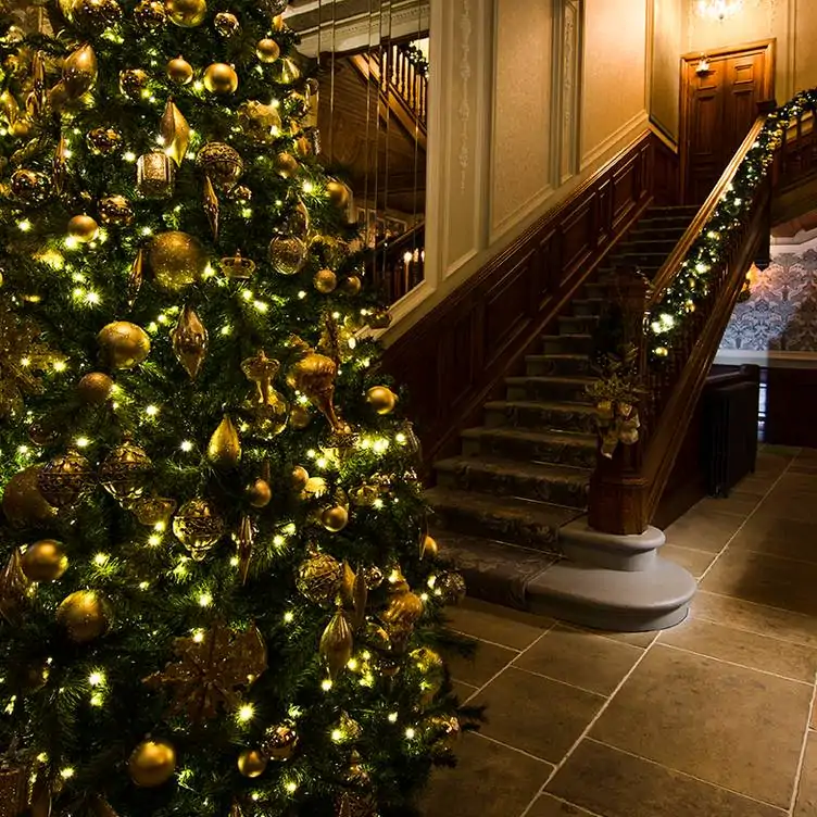 Entrance and staircase at No. 35 at The Bonham, one of the best restaurants for Christmas dinner, with tinsel and wreaths up the stairs and a Christmas tree in the foreground.