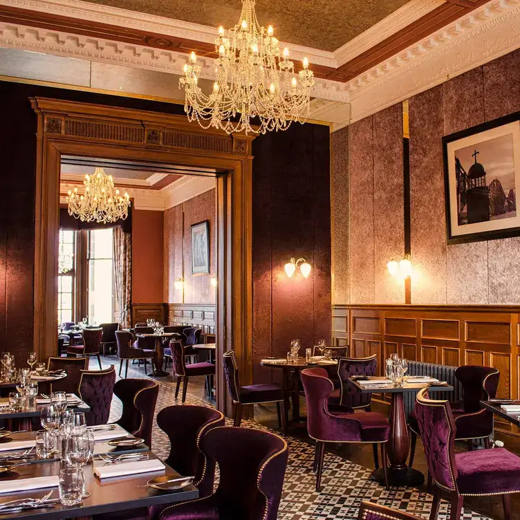 A dining area with purple velvet chairs, dark wood walls and chandeliers at No. 35 at The Bonham, one of the most festive restaurants in the UK.