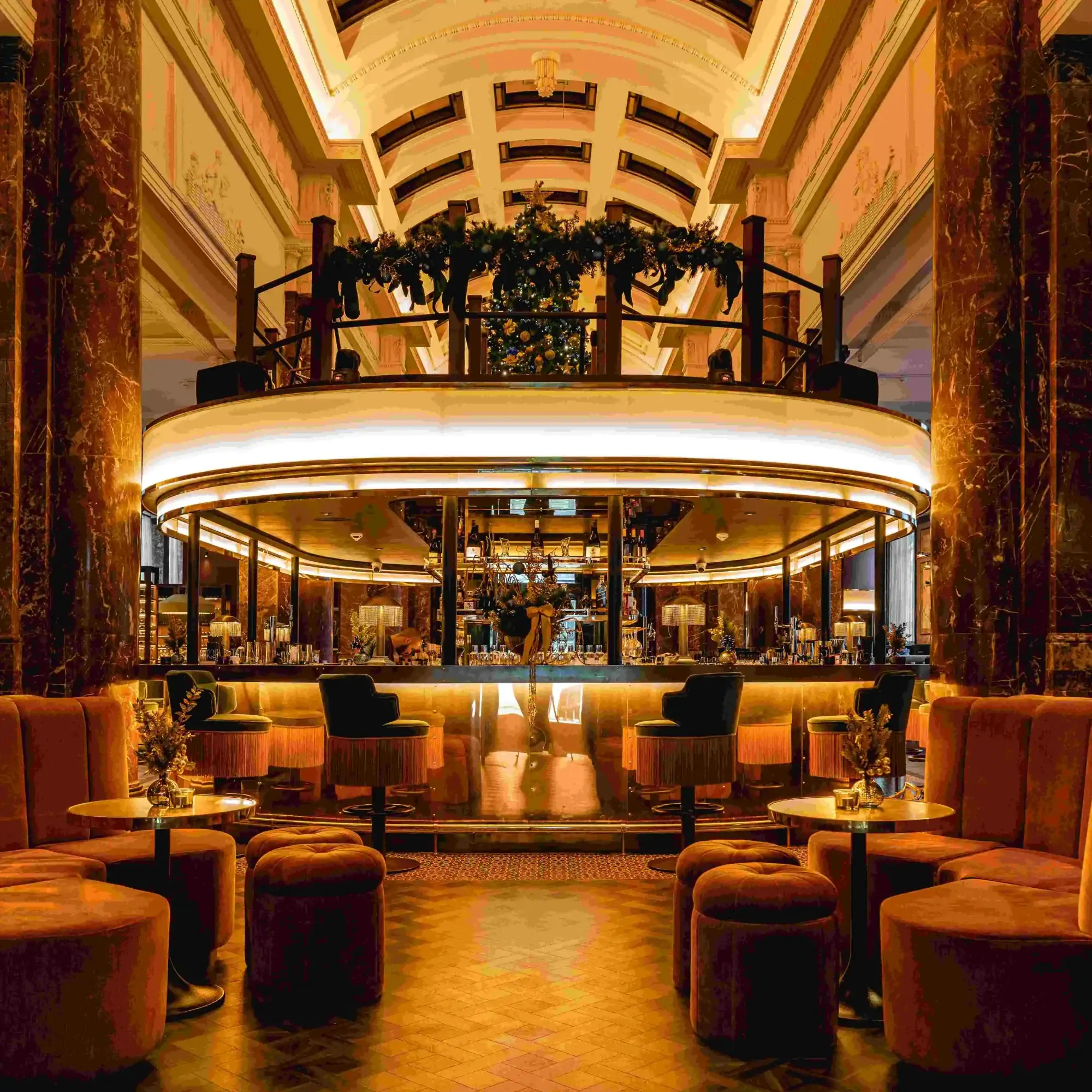 A circular bar area at Gaucho, one of the best Christmas dinner restaurants in the UK, with Christmas wreath decorations around the bar.