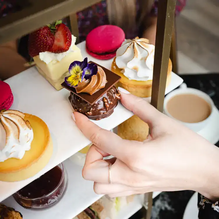 A diner reaching for a chocolate dessert from a platter of puddings at 20 Stories Restaurant, one of the best Christmas dinner restaurants in the UK.