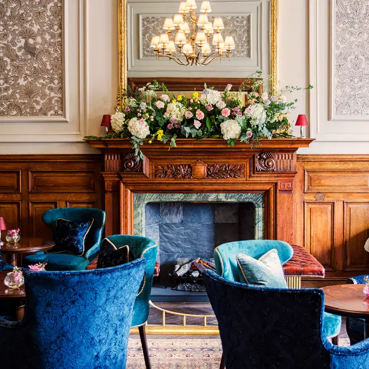 Velvet chairs around circular tables in front of a fireplace at No. 35 at The Bonham, one of the most festive restaurants in the UK.