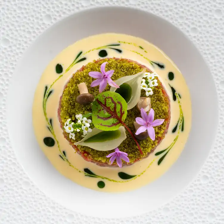 A soup dish topped with leaves and edible flowers from the menu at Clos Maggiore, one of the best Christmas restaurants in London.